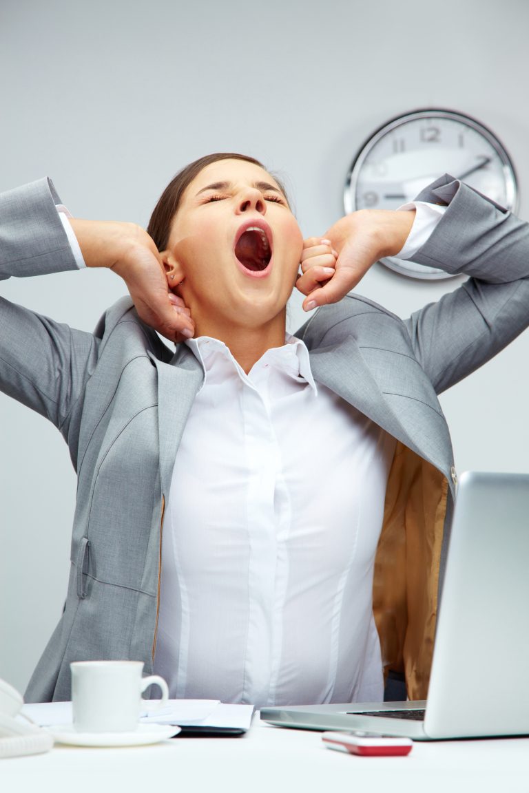 Tired office manager stretching herself and yawning