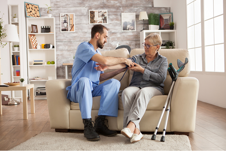 male-nurse-using-digital-blood-pressure-device-senior-woman-nursing-home